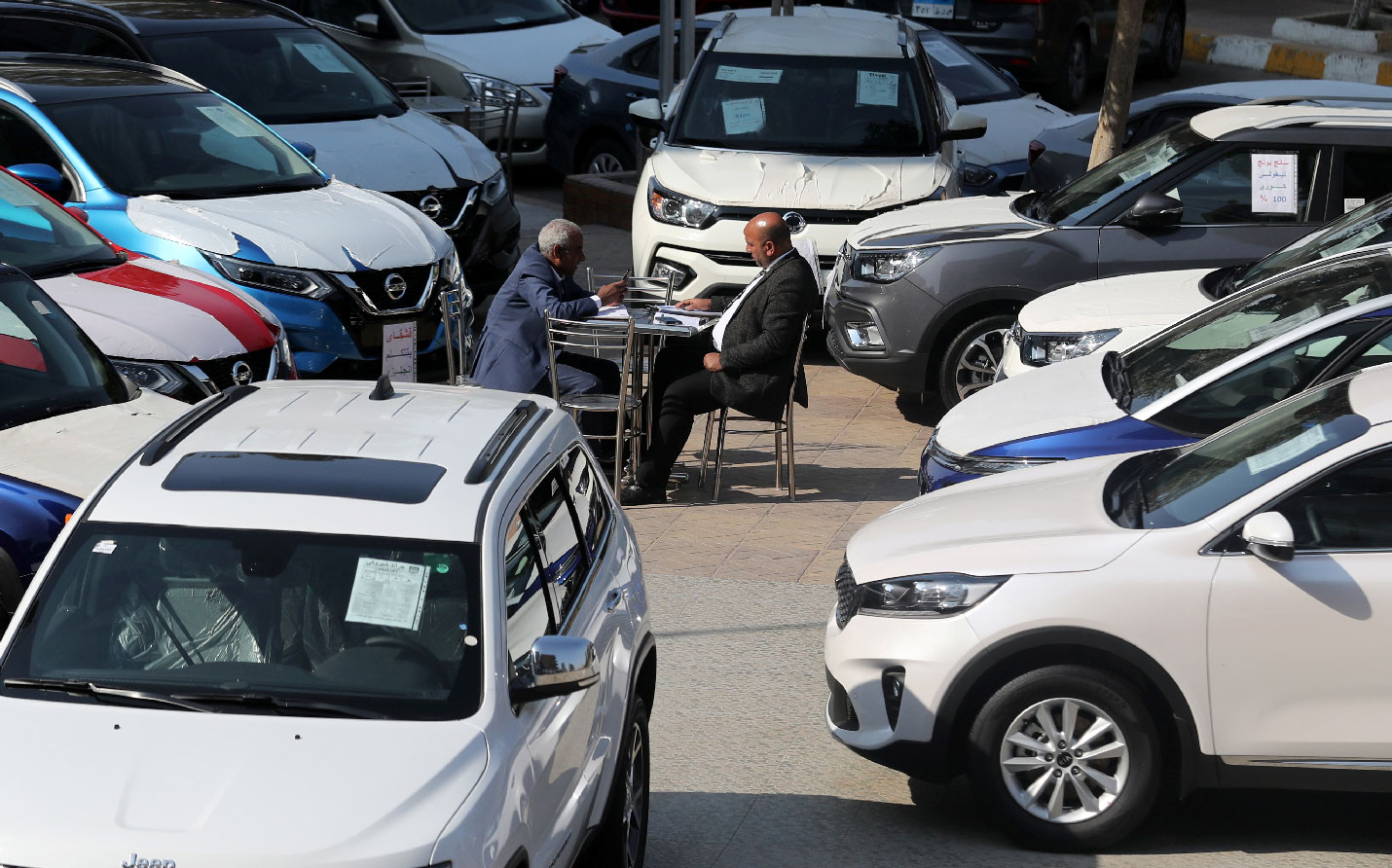 A customer sits with a sales representative at a car dealership where dozens of vehicles are on display in Cairo, Egypt, March 7, 2019.