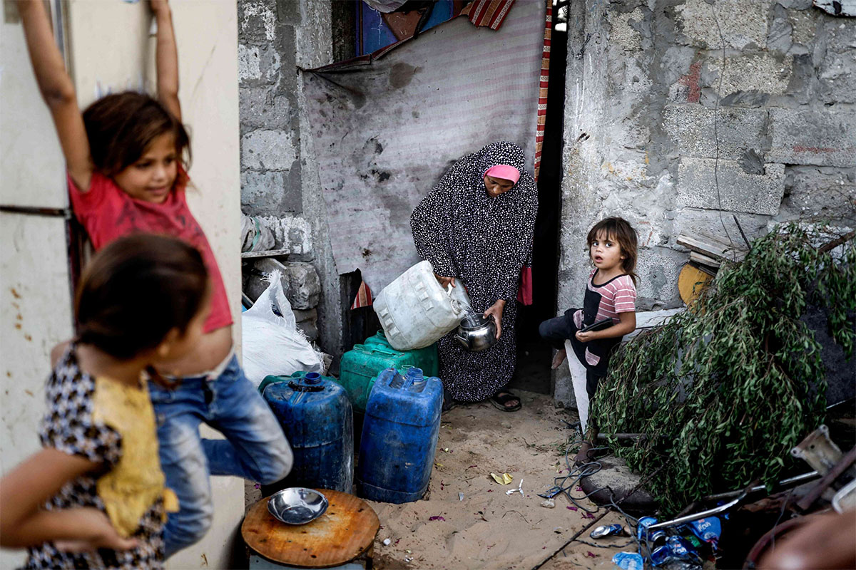 A Palestinian woman cleans a teapot with tap water drawn from a cistern in a poor neighbourhood in Khan Yunis