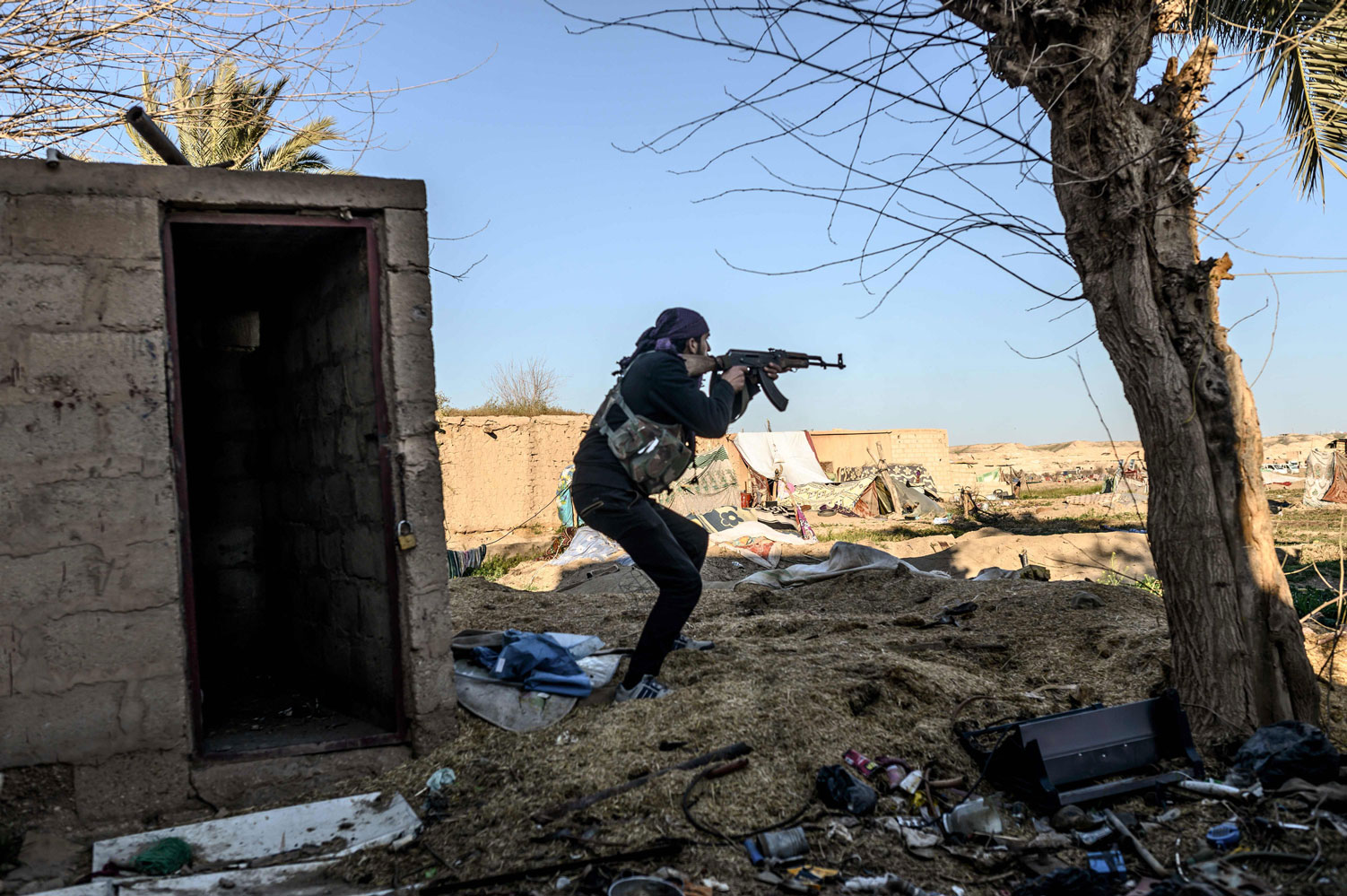 مقاتل من قوات سوريا الديمقراطية يطلق النار باتجاه معسكر لداعش في الباغوز