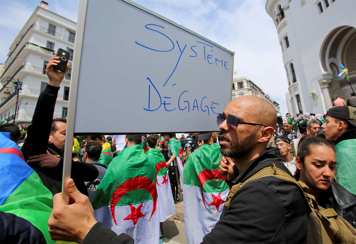 A man carries a sign reading "System, get out" during a protest seeking the departure of the ruling elite in Algiers