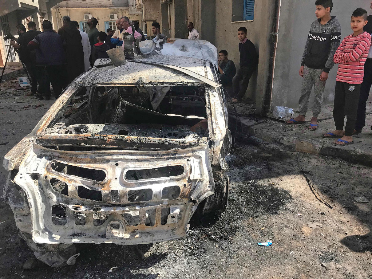 Libyans check a street in the capital Tripoli on April 17, 2019 in the aftermath of several rocket attacks the previous night