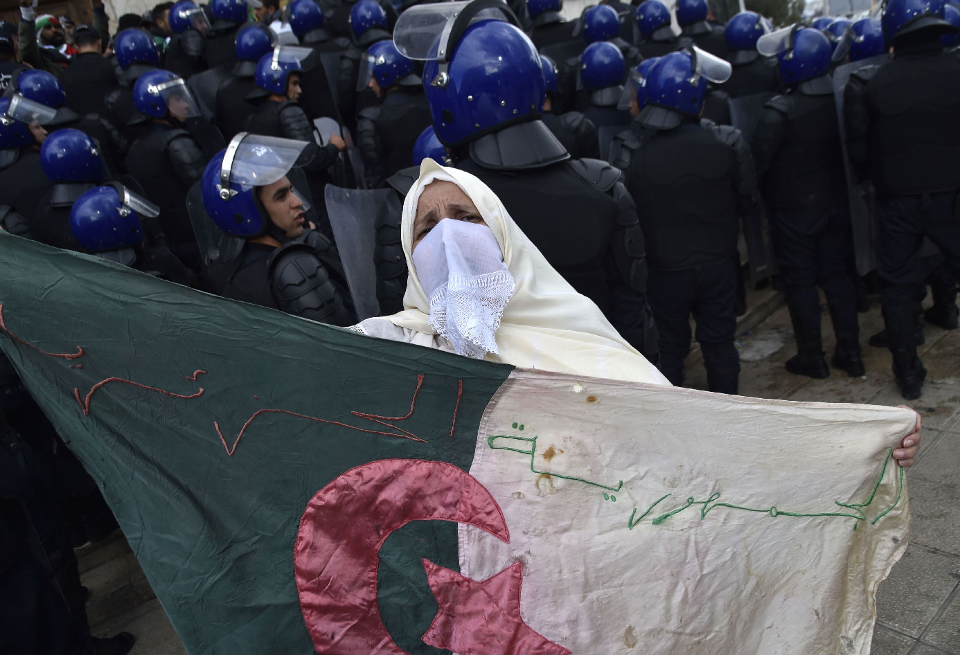 An Algerian woman holds a flag near security forces cordoning-off a protest area during an anti-system demonstration in the capital Algiers on April 10, 2019.