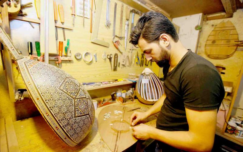 A Syrian refugee works on an oud, a pear-shaped stringed instrument made of wood, in Beirut