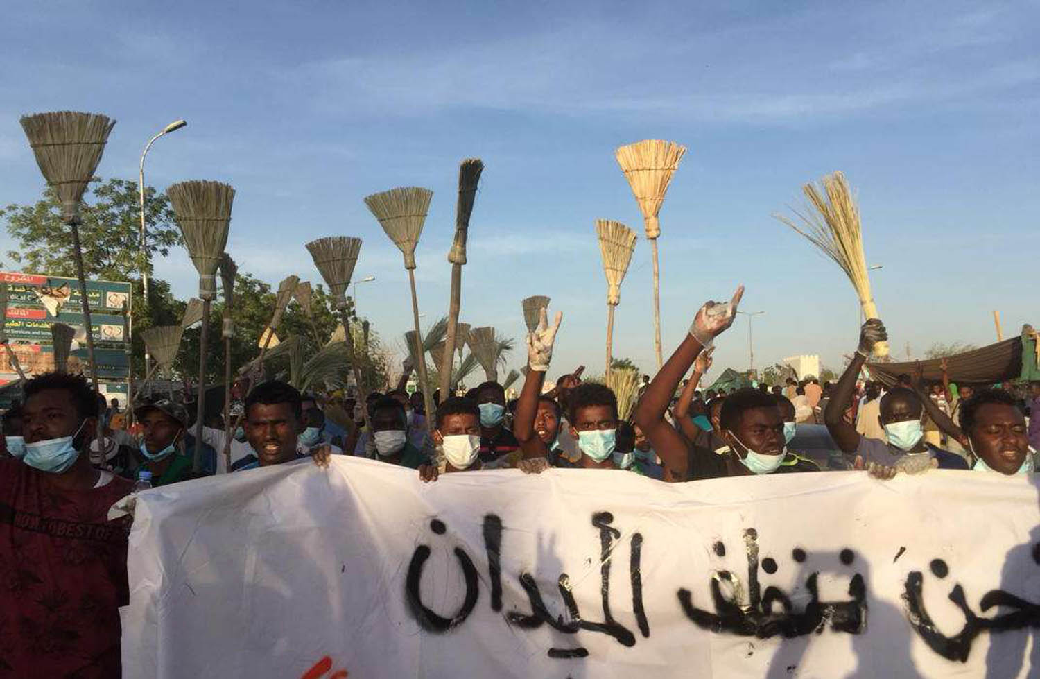 سودانيون يتظاهرون رافعين المكانس أمام مبنى قيادة الجيش