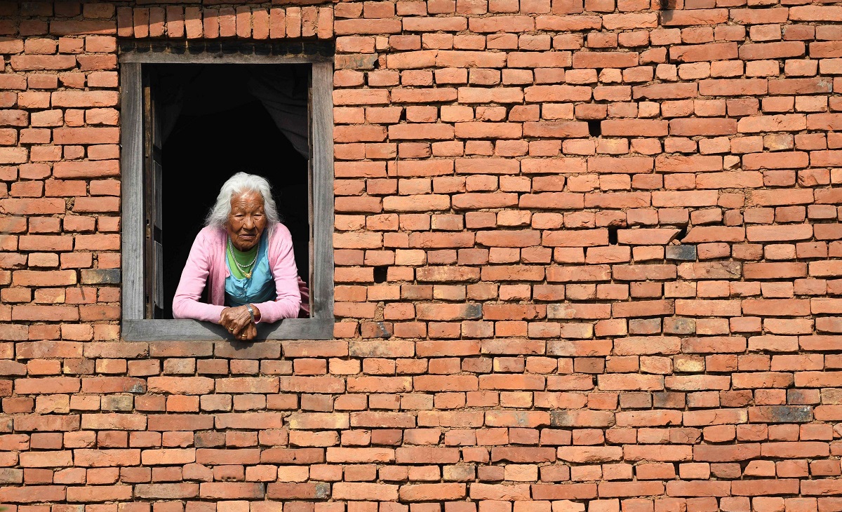 امرأة نيبالية مسنة تنظر من نافذة منزلها