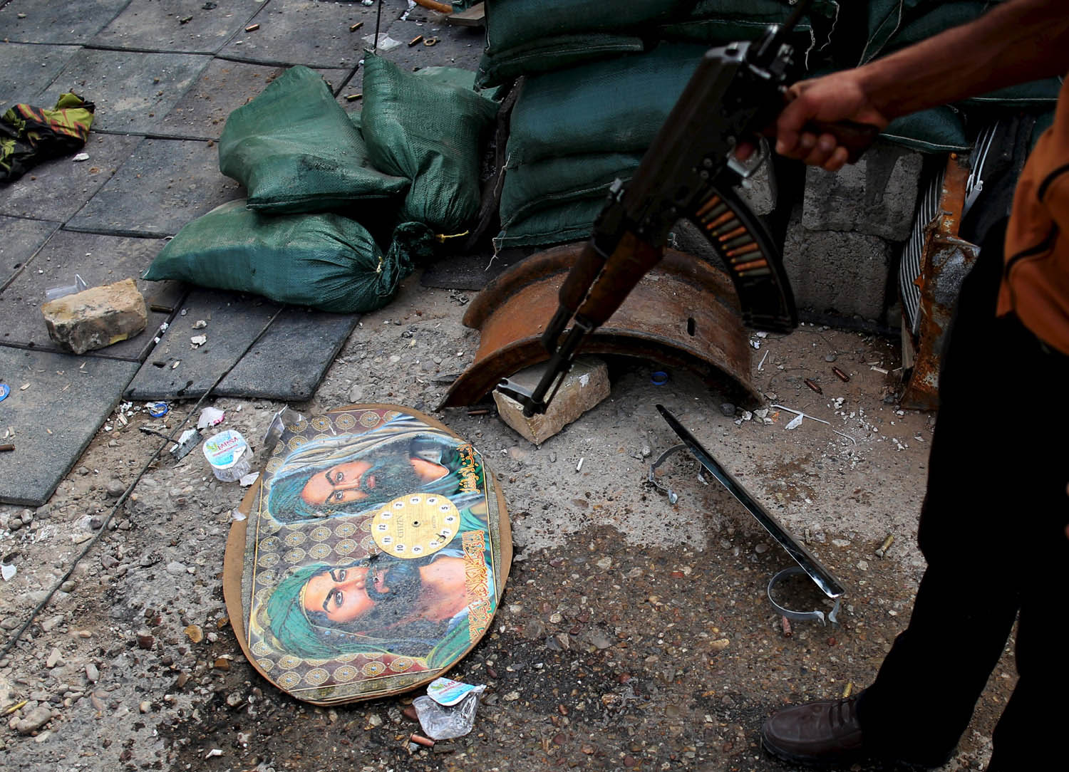 مقاتل من الأكراد يشير إلى صور دينية بعد اشتباك مع قوات شيعية في طوز خورماتو في العراق