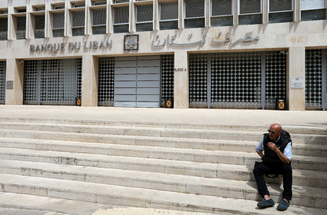 A man sits on the stairs in front of the central bank in Beirut
