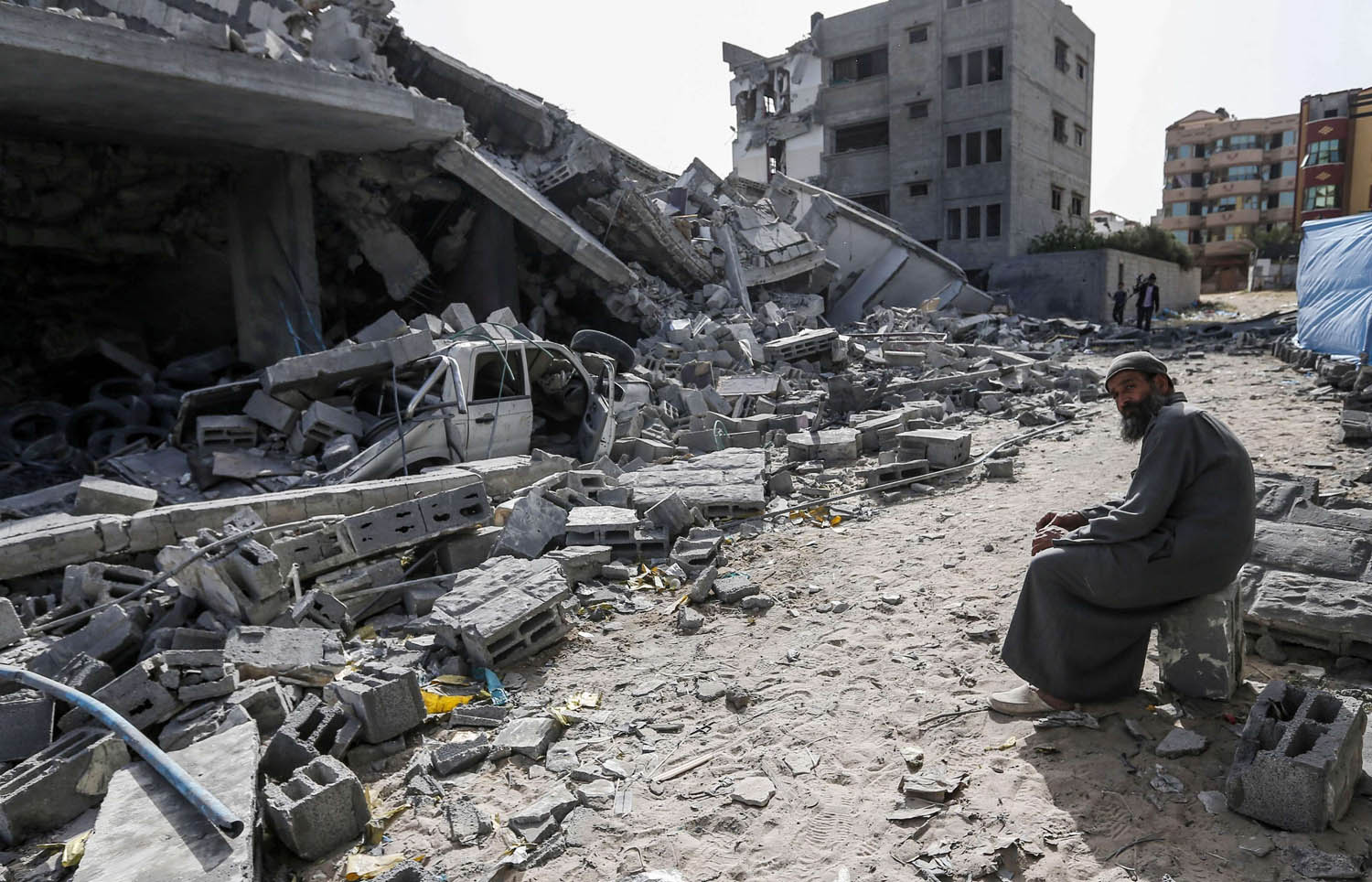 فلسطيني يجلس أمام مبنى دمرته غارات إسرائيلية في غزة