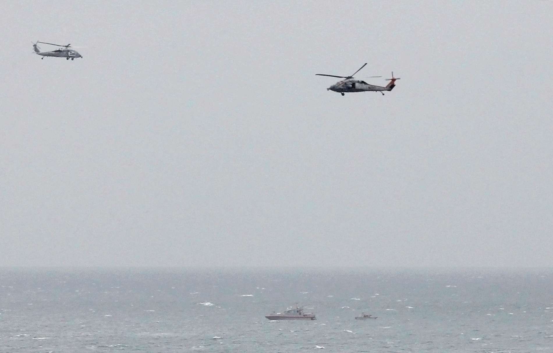 Iranian Revolutionary Guard boat is seen near the U.S. aircraft carrier USS George H. W. Bush in the Strait of Hormuz as U.S. Navy helicopters hover nearby