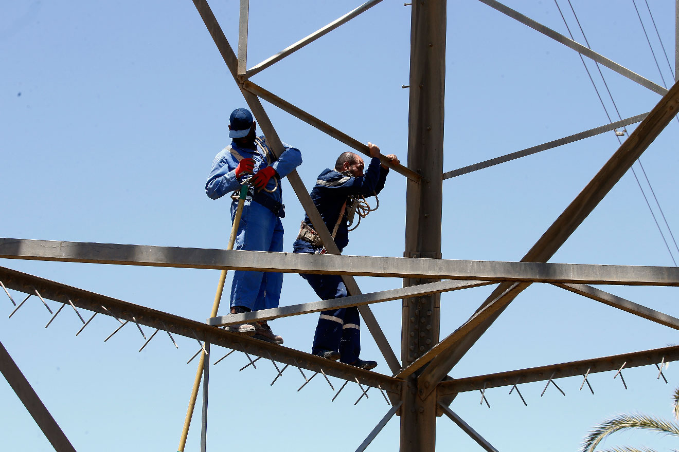 Workers operate on high voltage towers after they were damaged by fighting, south of Tripoli