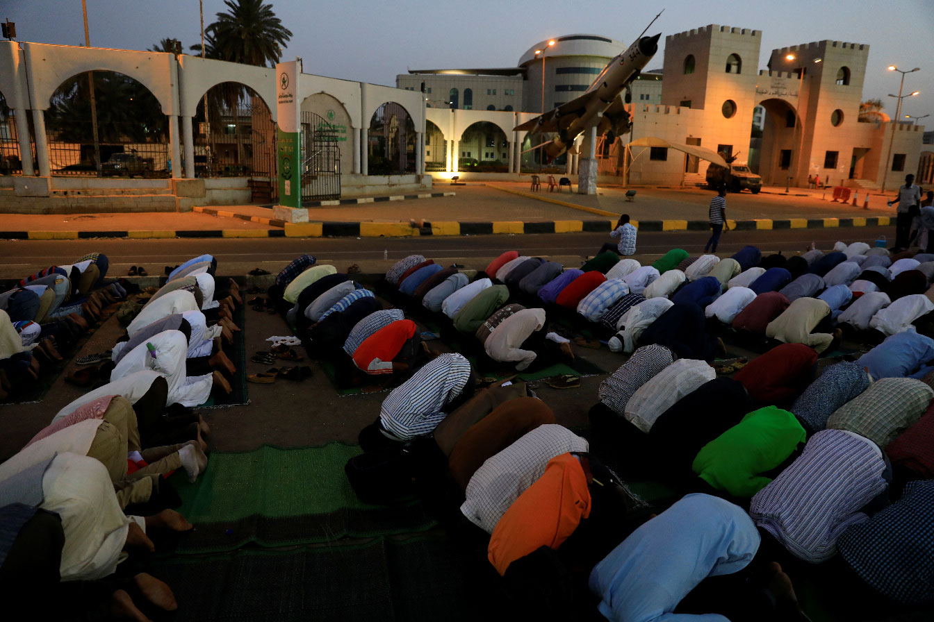 Sudanese protesters pray in front of the defense ministry compound in Khartoum