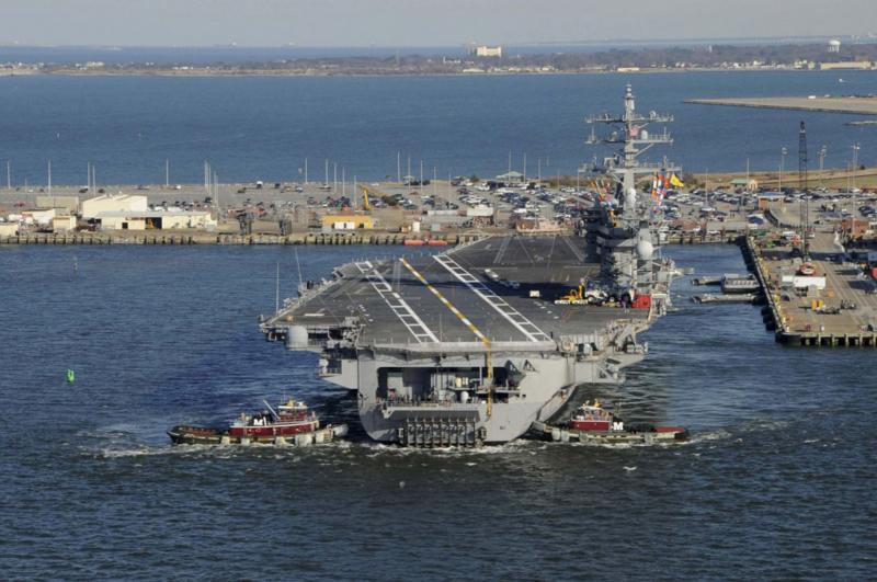 2013 file picture shows tug boats assisting the Nimitz-class aircraft carrier USS Dwight D. Eisenhower (CVN 69) as it pulls away from the pier at Naval Station Norfolk, Virginia