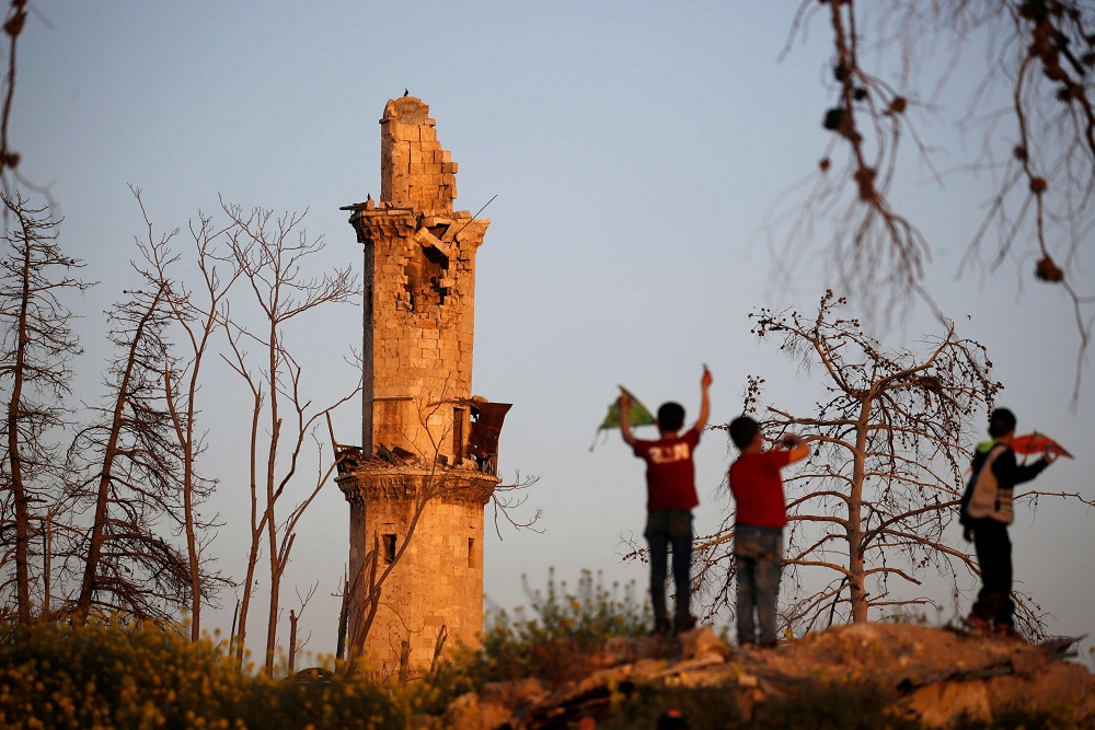 فتيان يلعبون بالقرب من مسجد  تاريخي بمئذنة تالفة في مدينة حلب القديمة 