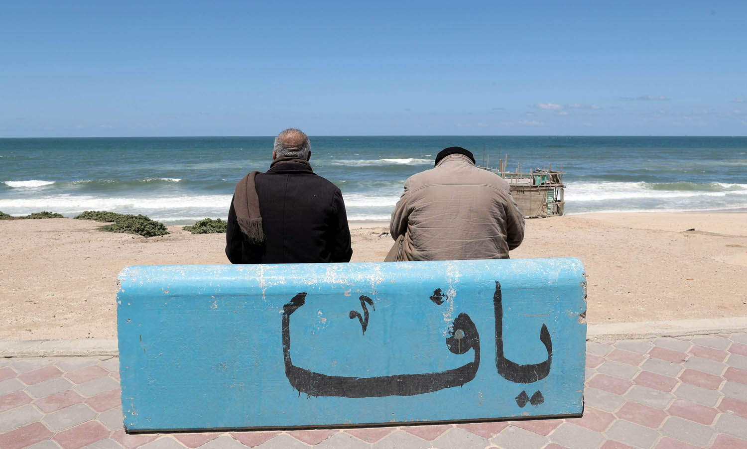 فلسطينيان يجلسان على ساحل البحر في غزة