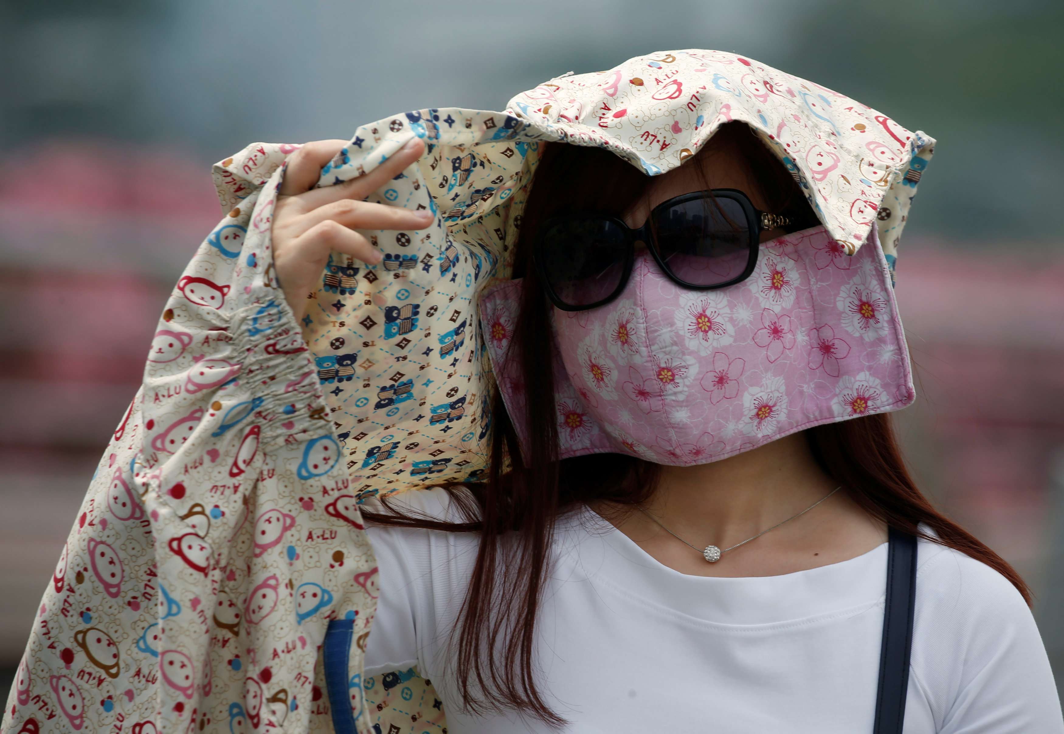 امرأة ترتدي قناعا لتحمي وجهها من أشعة الشمس في سنغافورة