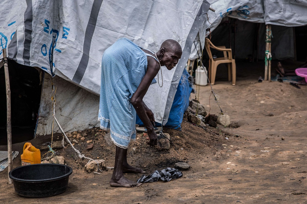 امرأة سودانية مصابة بالسل في العمود الفقري تنظف حول خيمتها في جوبا