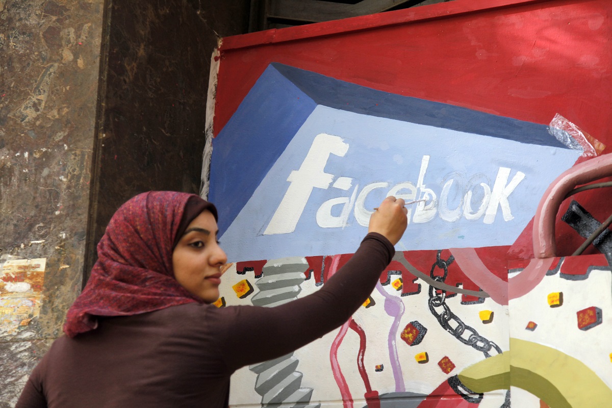 طالبة مصرية ترسم شعار فيسبوك على لوحة جدارية تخلد ذكرى الثورة التي أطاحت بحسني مبارك 