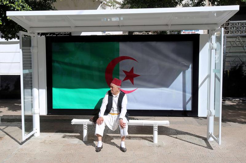 A man sits at a bus station decorated with the national flag during a protest demanding the removal of Algeria’s ruling elite in Algiers