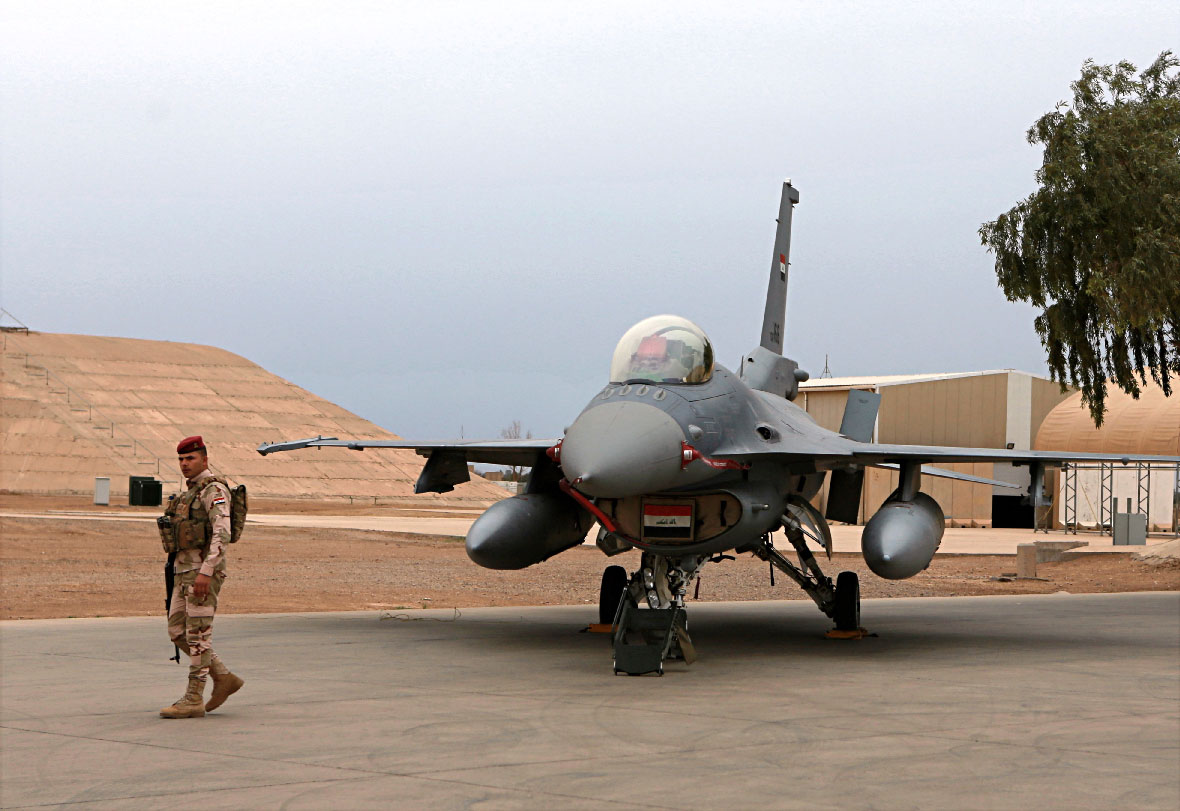 An Iraqi army soldier stand guard near a US-made fighter jet at the Balad Air Base