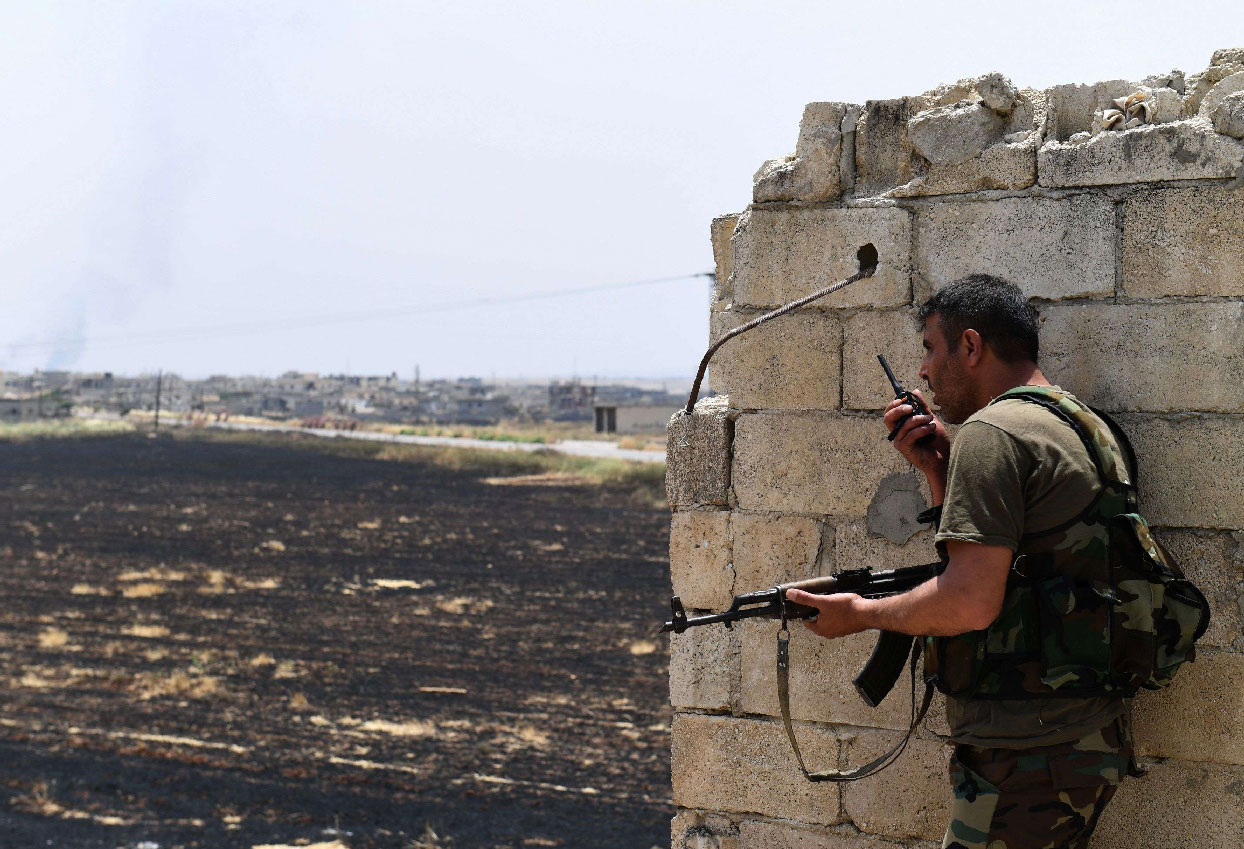 A fighter with the Syrian regime forces holds a position in Syria's Hama province