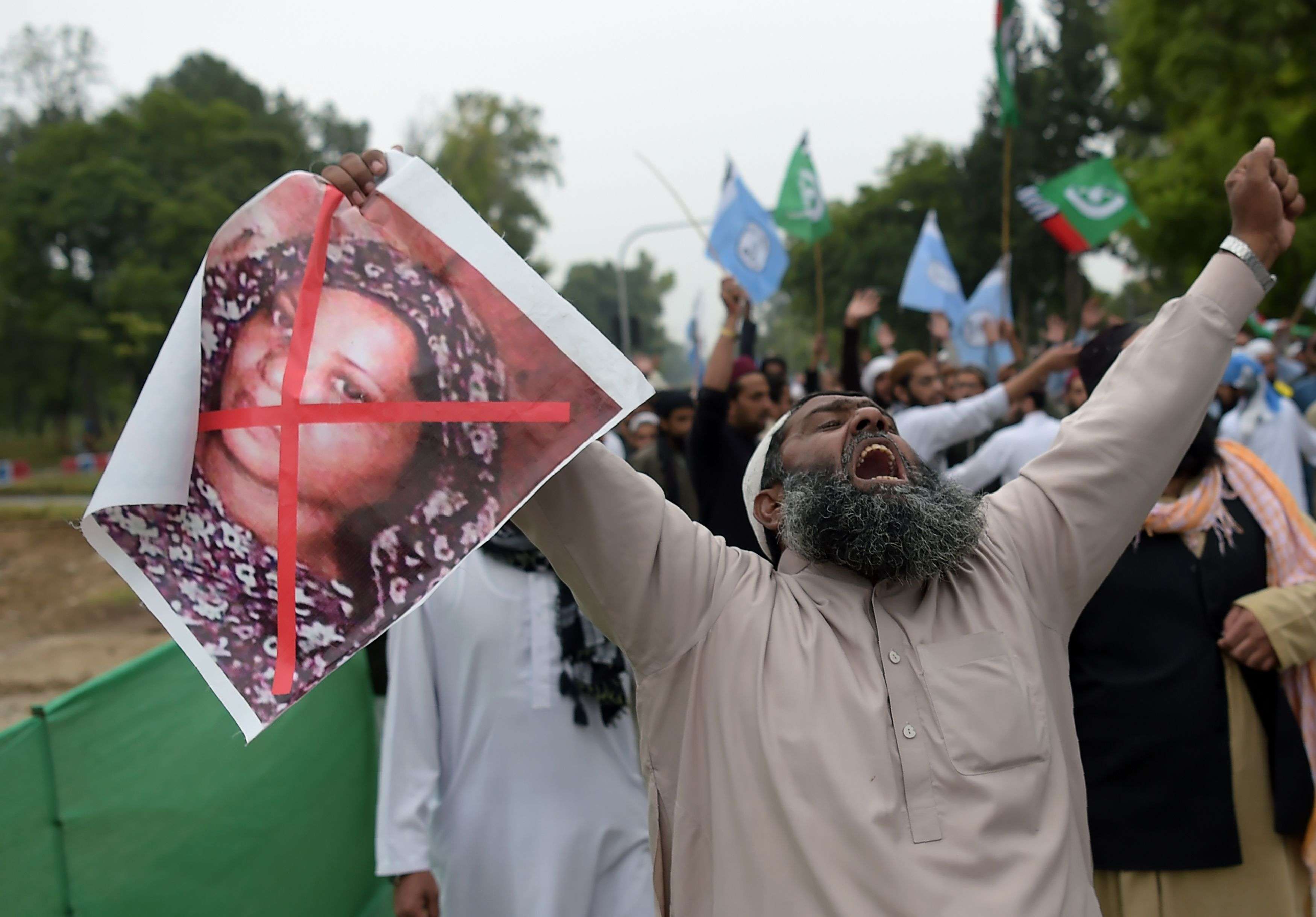 أحد المؤيدين الباكستانيين لحزب ديني متشدد حاملا صورة لامرأة مسيحية خلال مظاهرة احتجاج عقب قرار المحكمة العليا بتبرئتها من التجديف