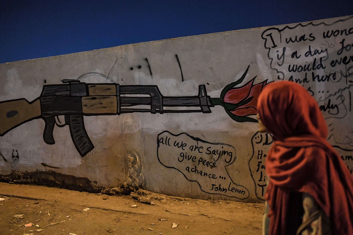 فتاة سودانية تنظر إلى جدارية تجسد بندقية في الخرطوم