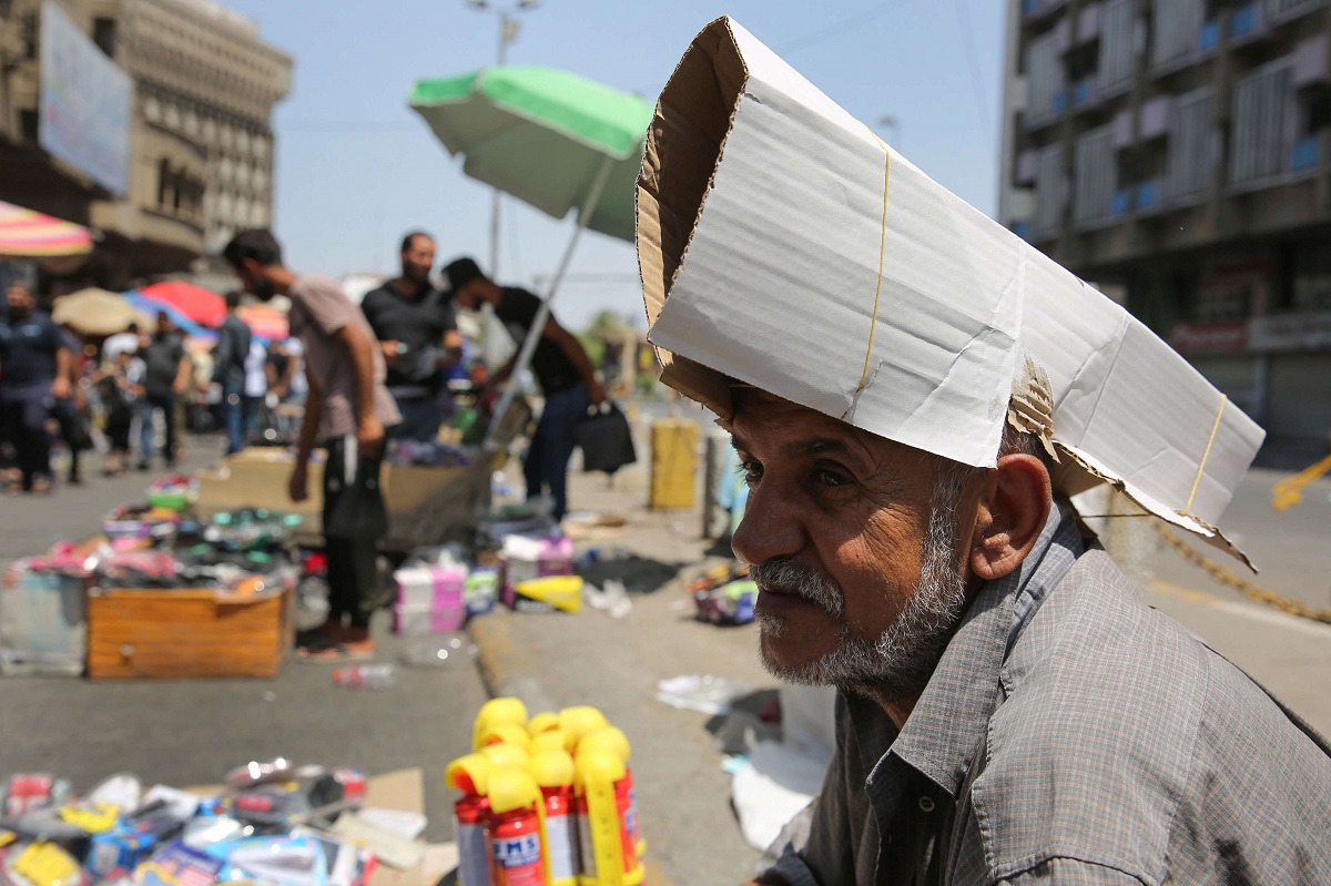بائع متجول عراقي يحمي رأسه من الشمس باستخدام الكرتون  خلال موجة الحر في بغداد
