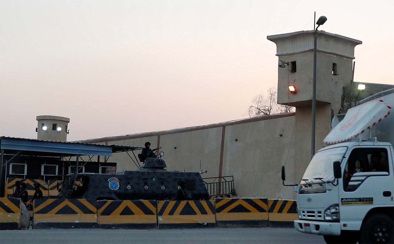 A truck drives in front of security and riot police guards, outside Cairo's Tora prison