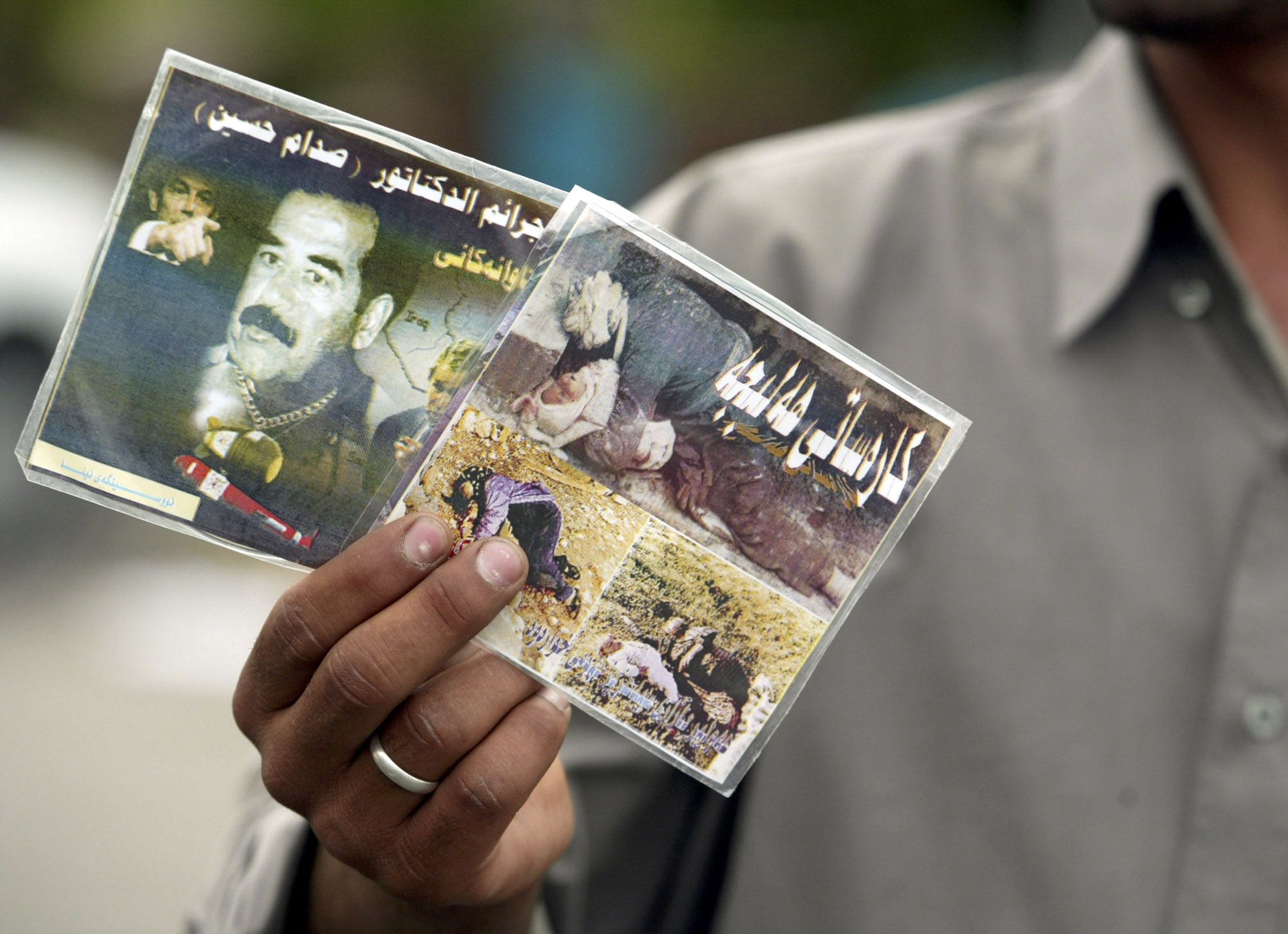 An Iraqi street vendor holds video compact discs titled "crimes of the dictator Saddam Hussein" in Kurdish