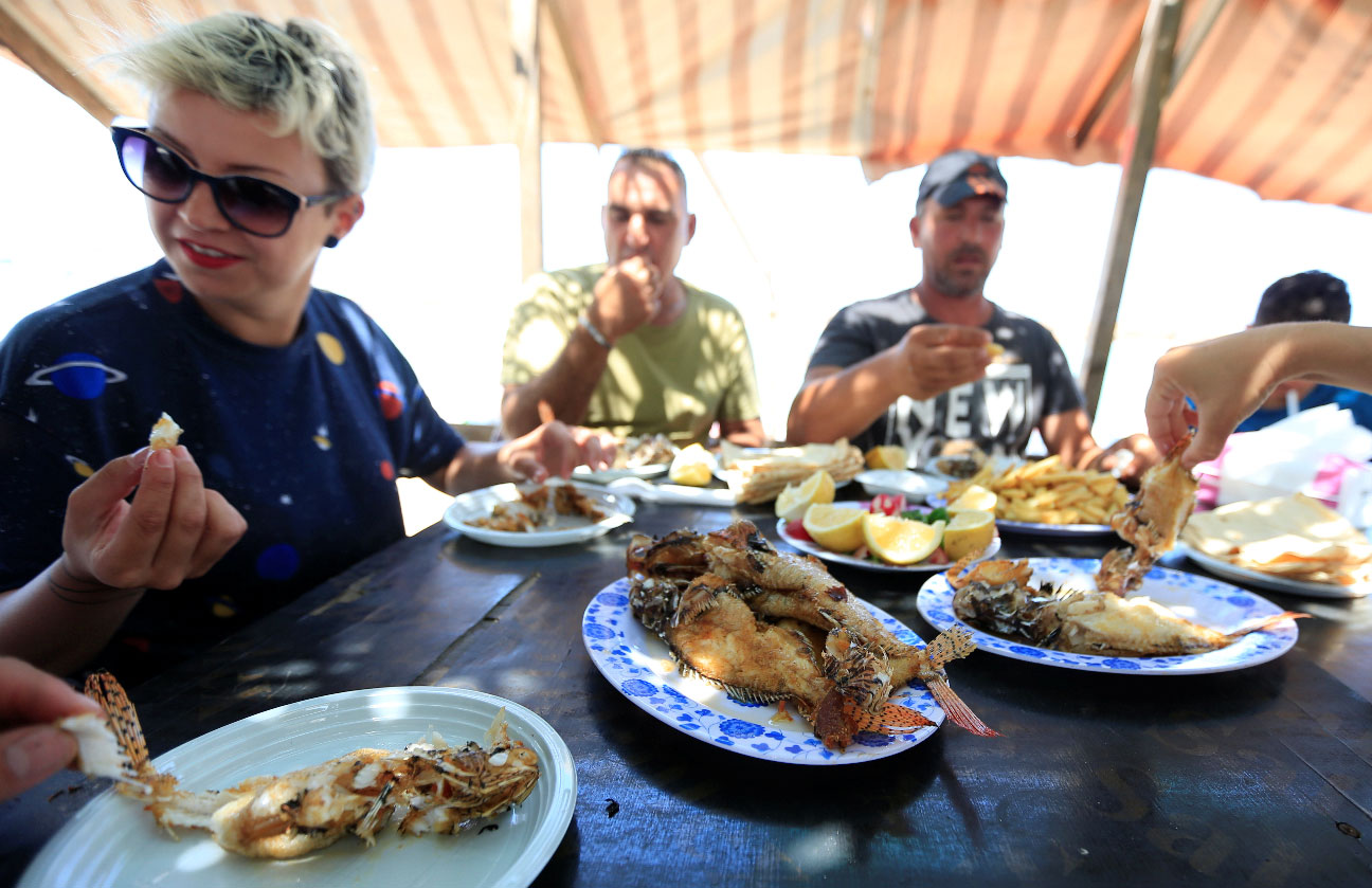 Jina Talj, an environmentalist, eats fried lionfish in Sarafand, Lebanon