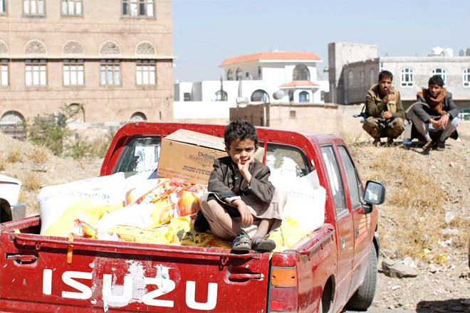 A son of a Houthi supporter sits on the back of a truck with food aid in Sana’a