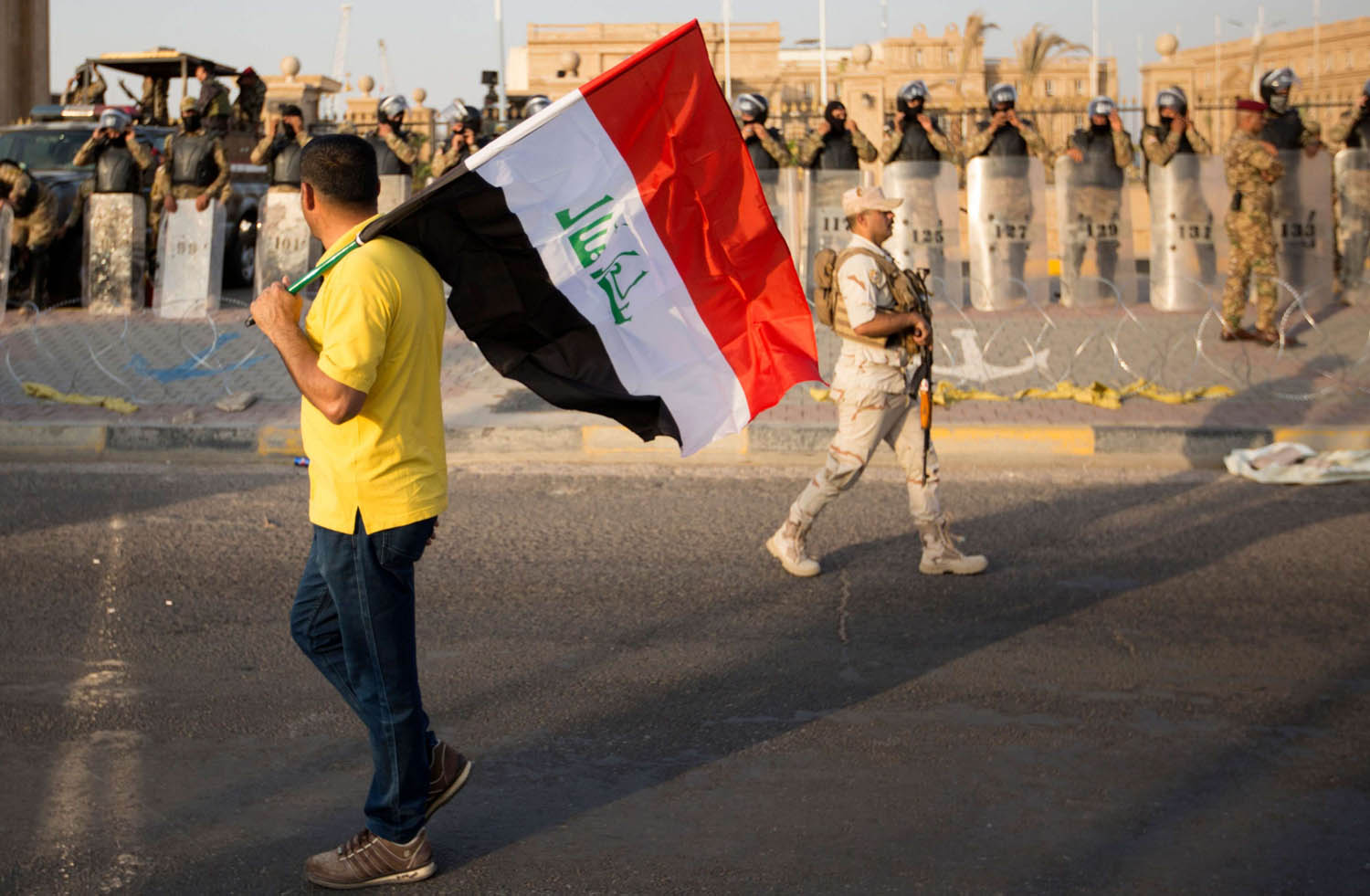 متظاهر عراقي يحمل علما أمام مبنى مجلس محافظة البصرة