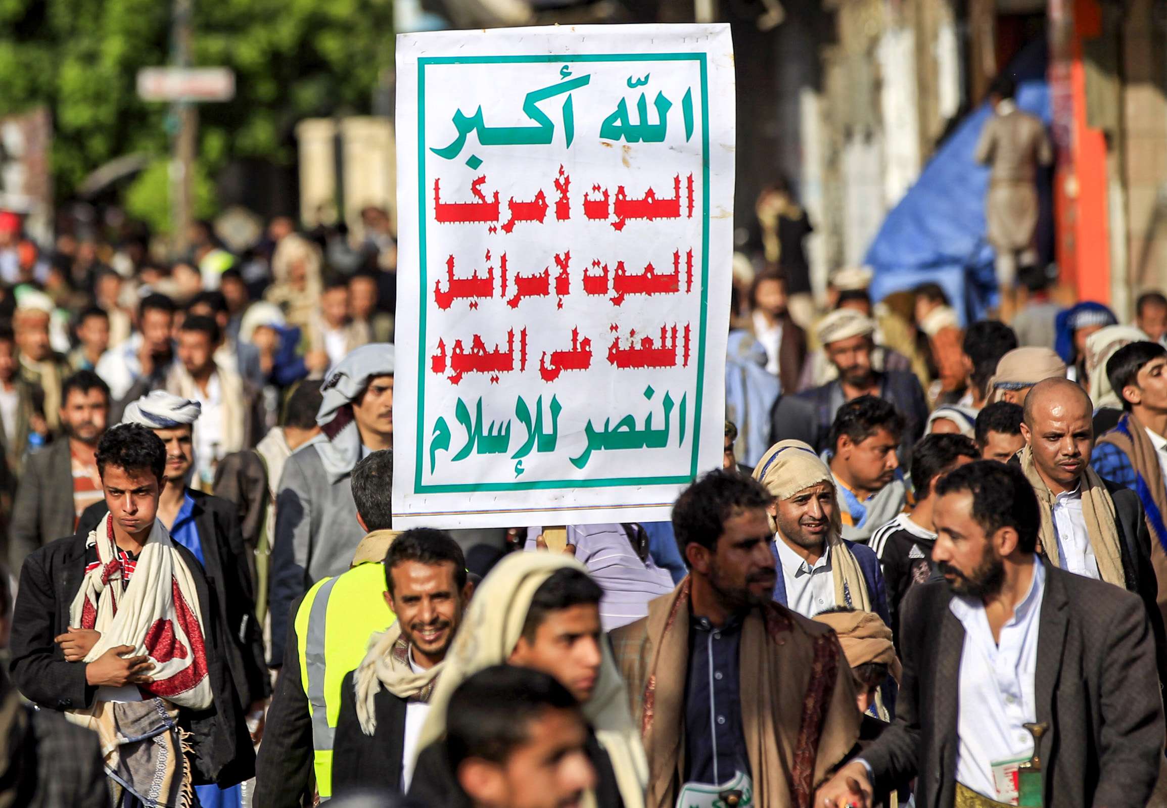 Supporters of Yemen's Huthi rebels march with the groups emblem, reading in Arabic "God is Great, death to America, death to Israel, curse upon the Jews, victory for Islam"