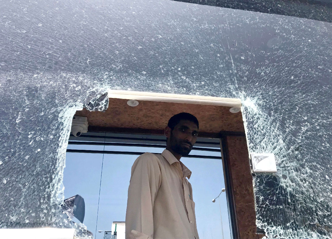 A parking employee looks at a damaged glass window at Saudi Arabia's Abha airport