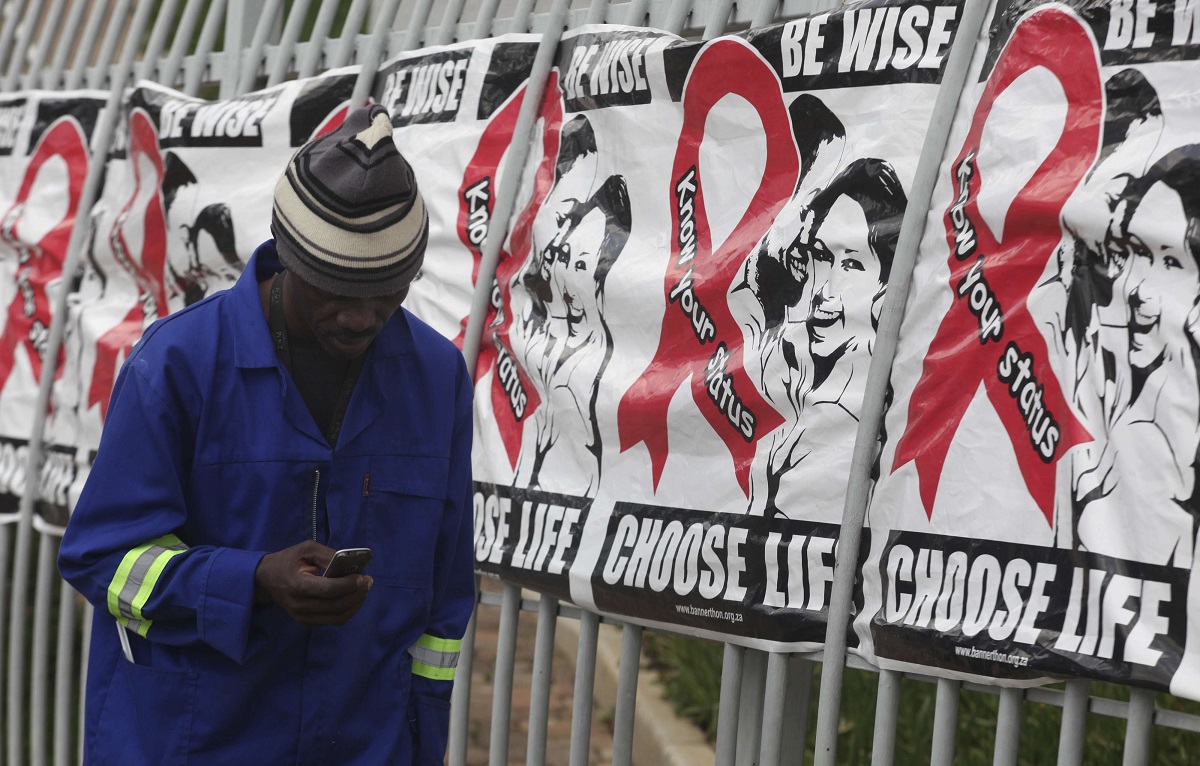 رجل يجري مكالمة أمام لافتات اليوم العالمي للإيدز في جوهانسبرغ بجنوب إفريقيا