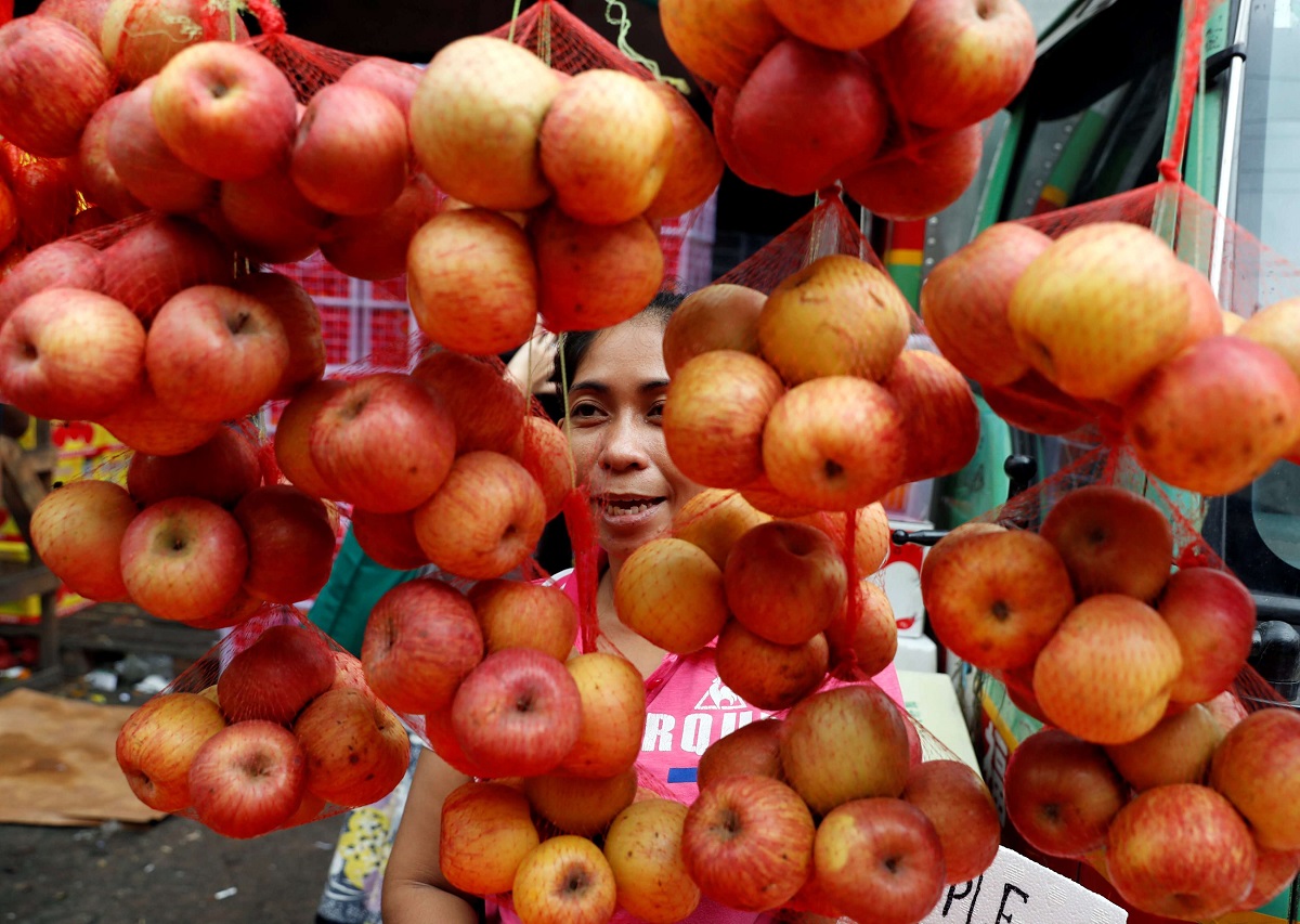 بائع فلبيني يعرض تفاحا في كشك فواكه في مانيلا