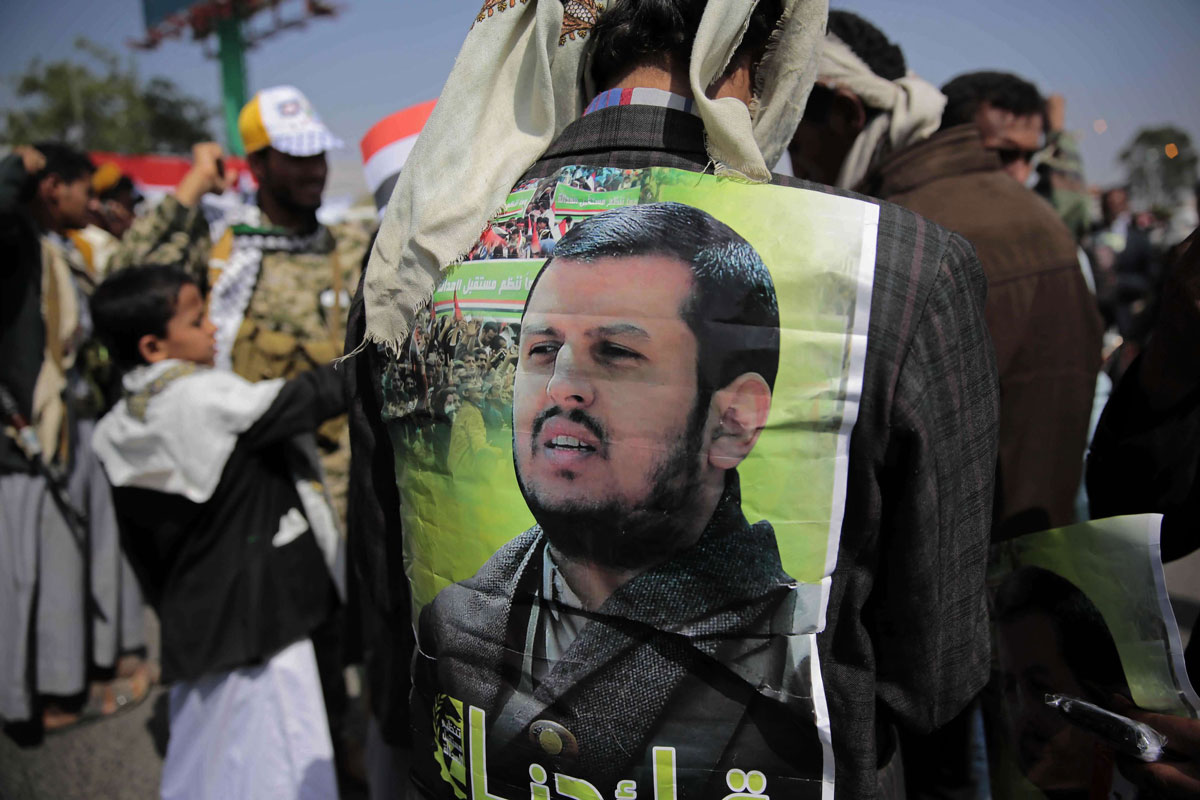 A Huthi supporter displays a poster of Abdel-Malek al-Houthi