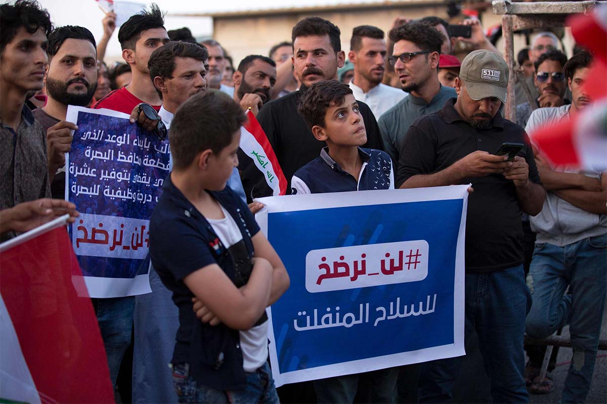 Iraqi protesters raise signs reading in Arabic "#WillNotSurrender to loose arms", during a demonstration outside outside the Basra local government headquarters last month