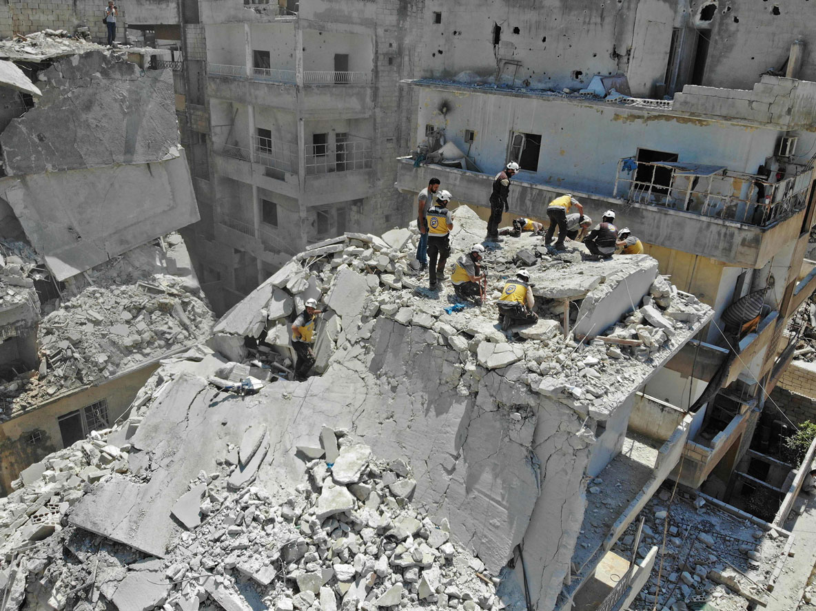 Members of the Syrian Civil Defence (White Helmets) search for victims at the site of a reported air strike on the town of Ariha