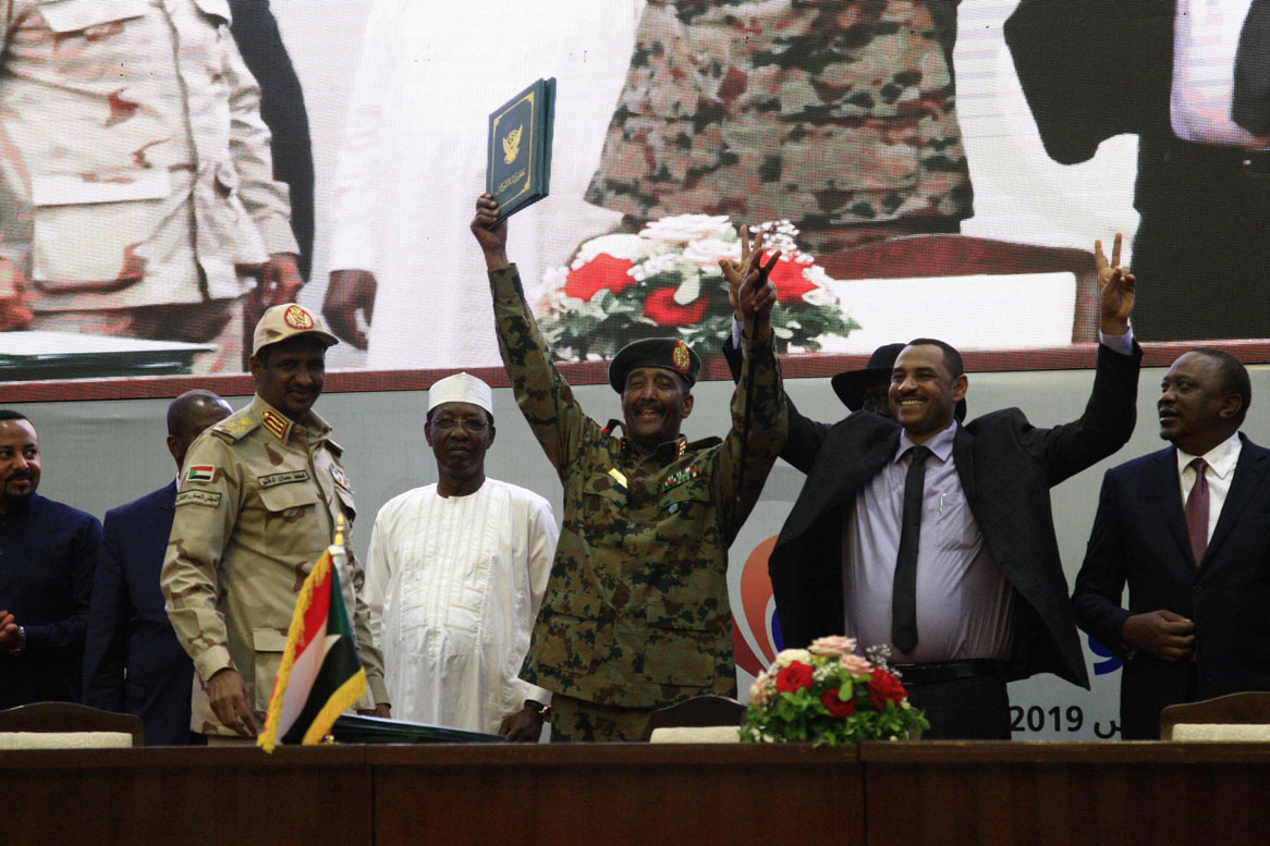 Sudan's protest leader Ahmad Rabie (2nd-R), flashes the victory gesture alongside General Abdel Fattah al-Burhan (C)