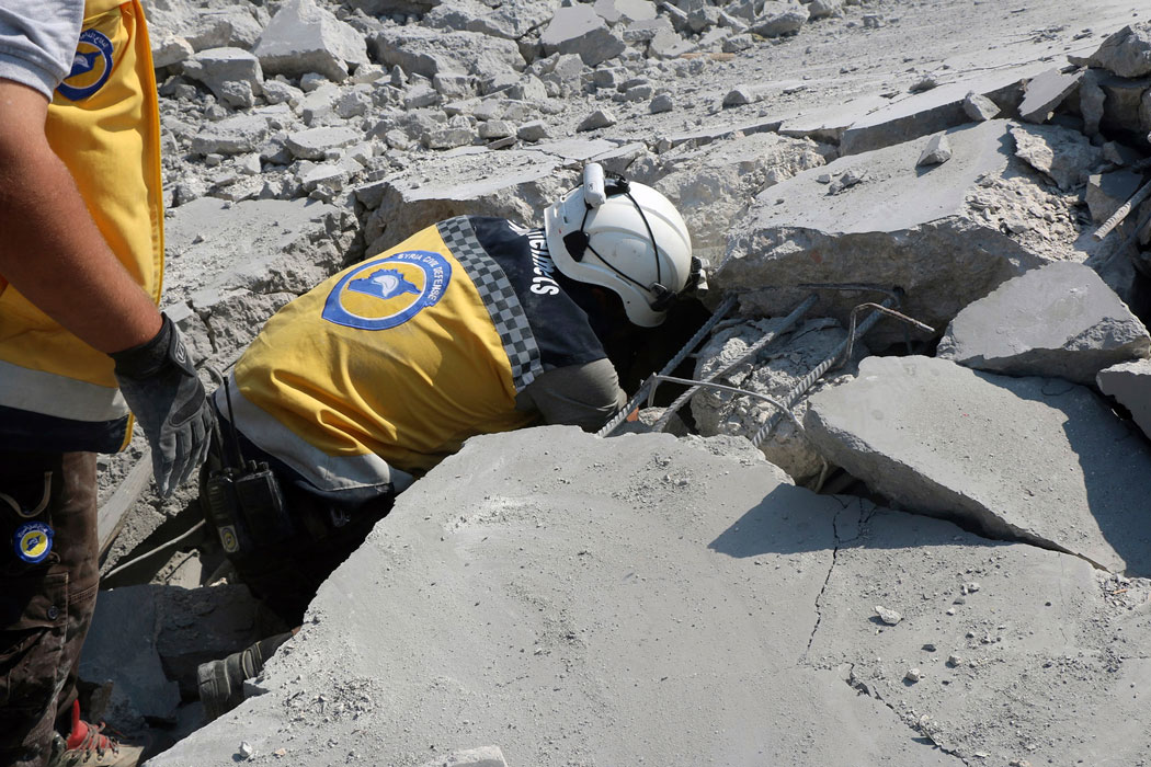 Syrian Civil Defense worker searching for victims from under the rubble of a destroyed building