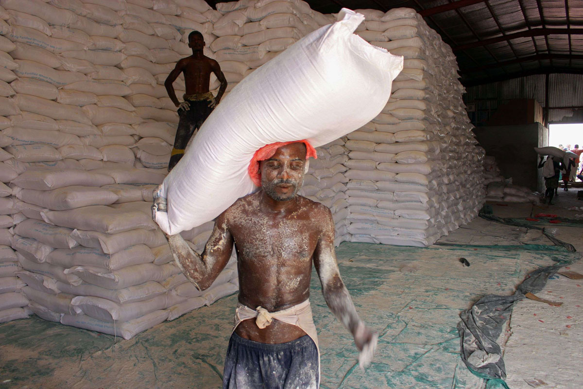 An aid worker carries a sack of flour in the northern Yemeni province of Hajjah
