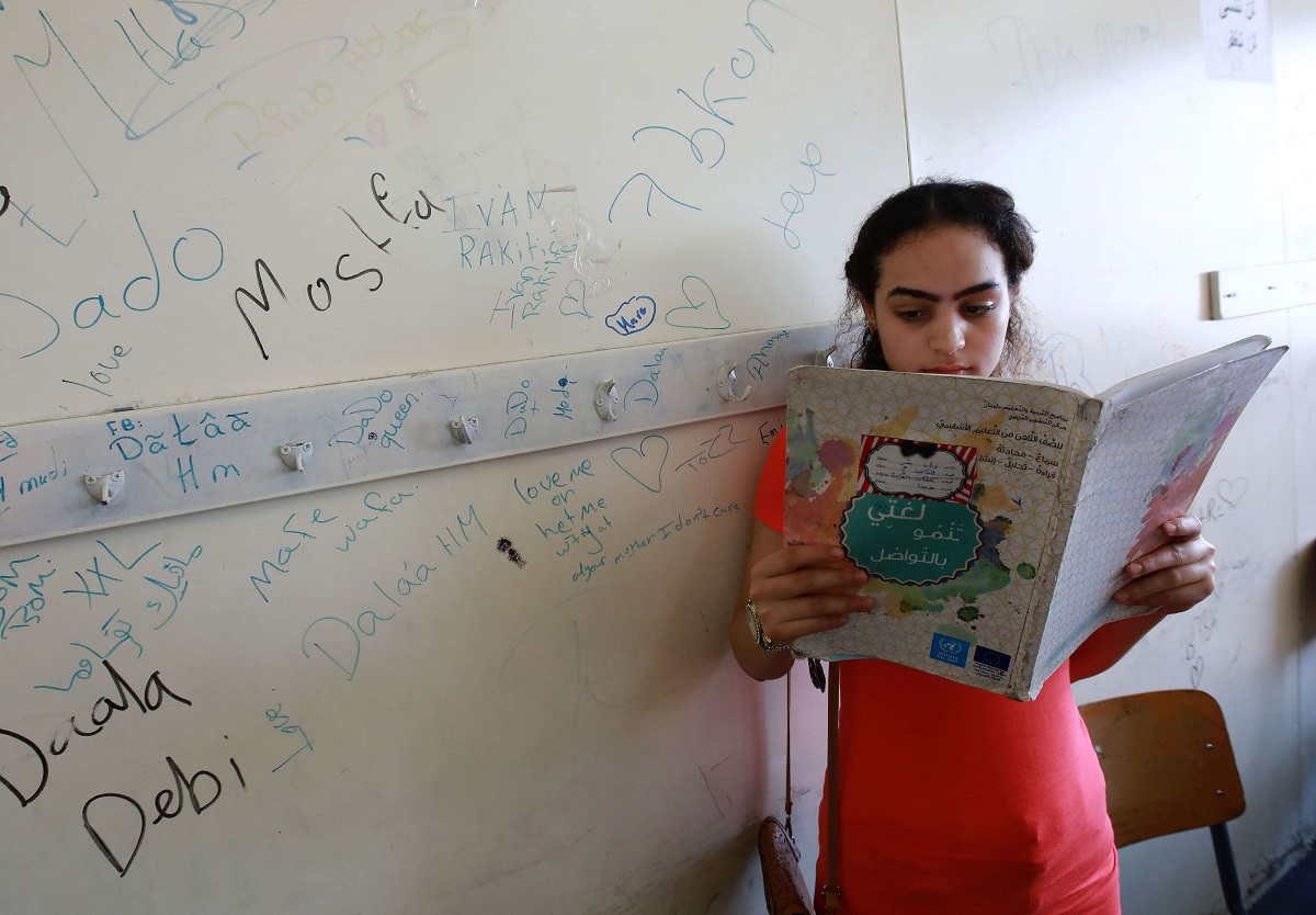 طفلة فلسطينية تقرأ قصة في مخيم بلبنان
