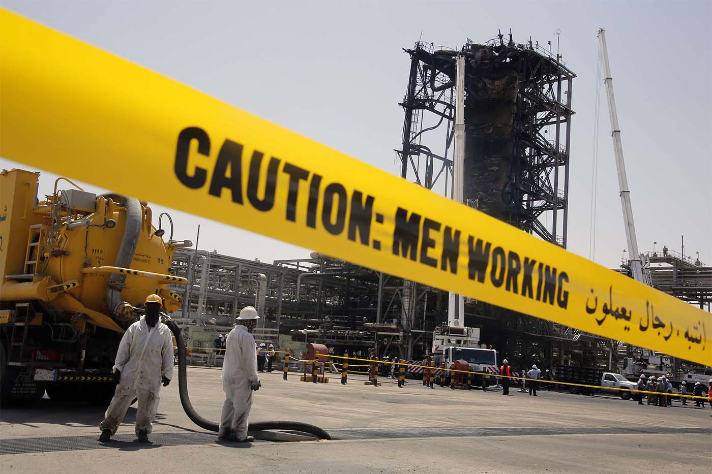 Workers work in front of the recent attack Aramco's oil processing facility in Khurais