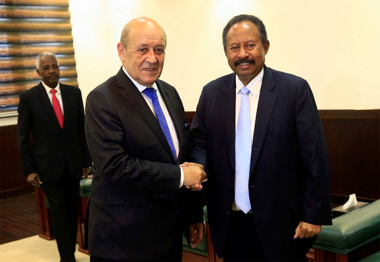 Sudan's PM Abdalla Hamdok shakes hands with French FM Jean-Yves Le Drian during their meeting in Khartoum