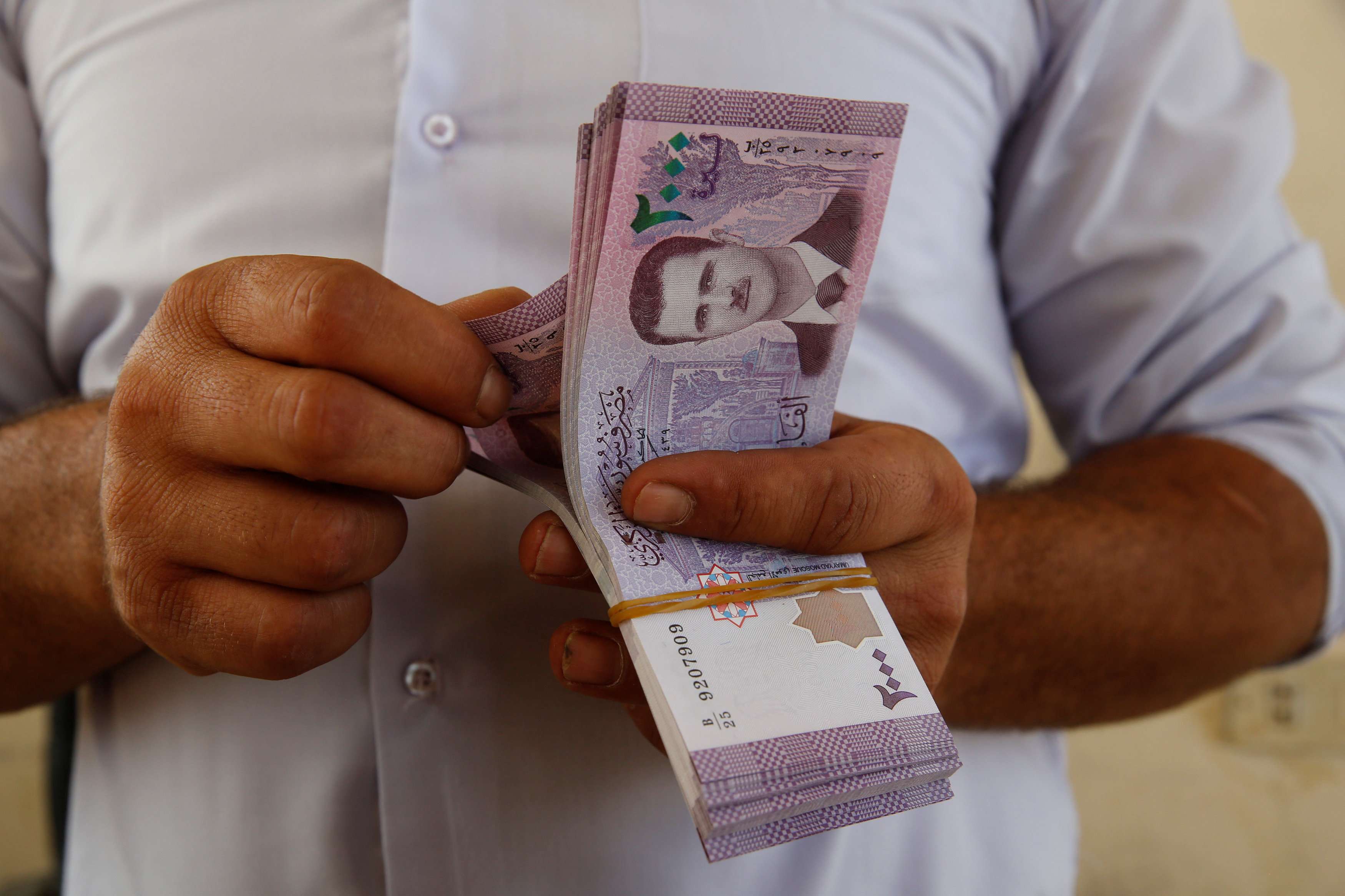 A Jordanian money changer holds Syrian currency