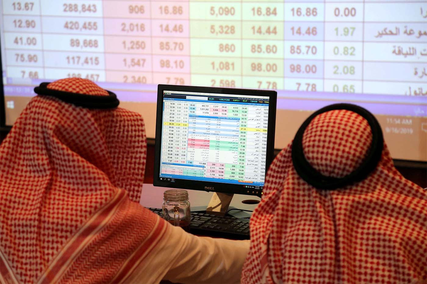 A Saudi man looks at the computer showing stock prices at ANB Bank in Riyadh