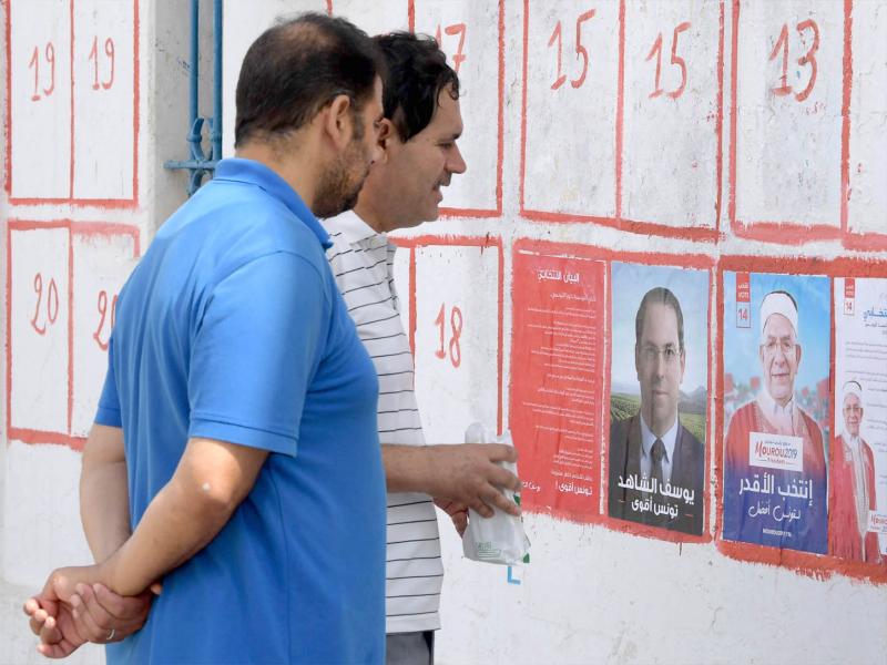 Tunisians look at posters of presidential candidates in Tunis