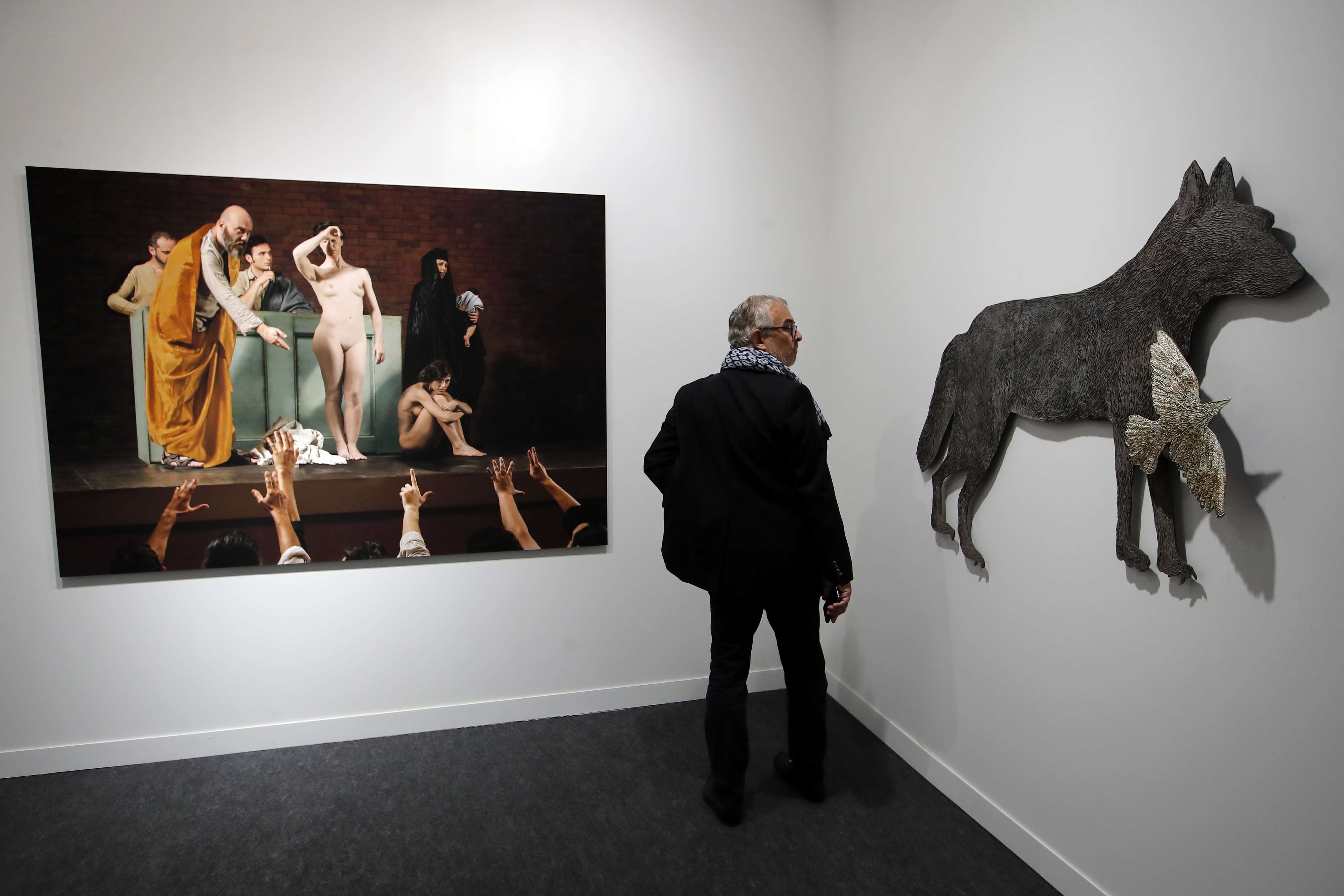 زائر يقف بين لوحة للفنان المصري معتز نصر (يسار) وعمل لفنان ألماني (يمين)