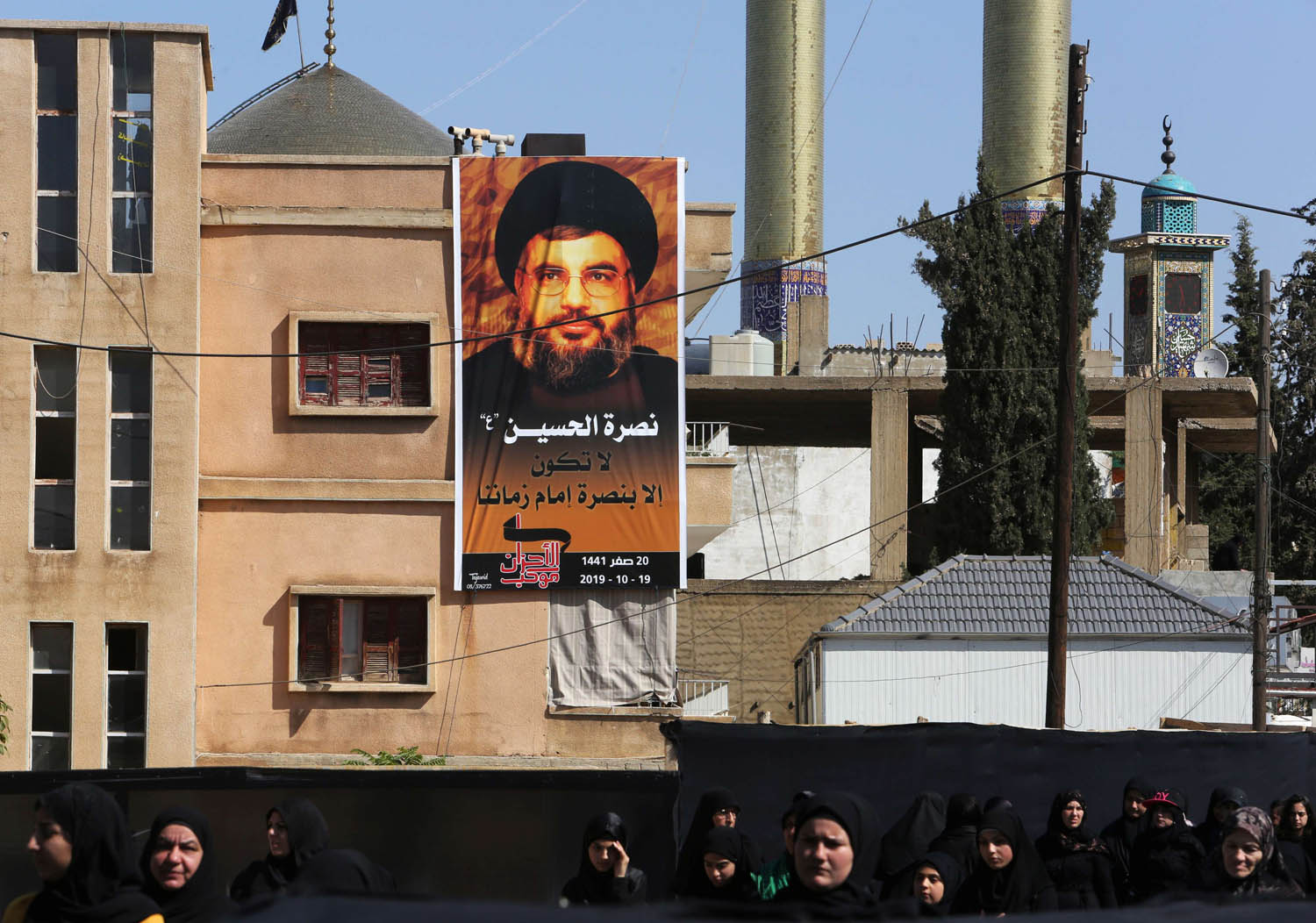 لبنانيات يقفن بالقرب من لوحة اعلان لزعيم حزب الله حسن نصرالله